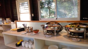 A buffet setup with various food items and utensils. - GOOSE NEST Garden B&B (Luye)