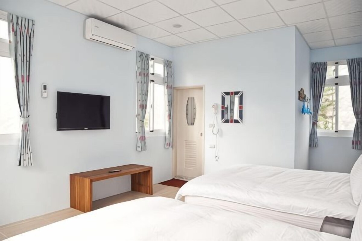 A bedroom with a bed, a TV, a bench, and a door.