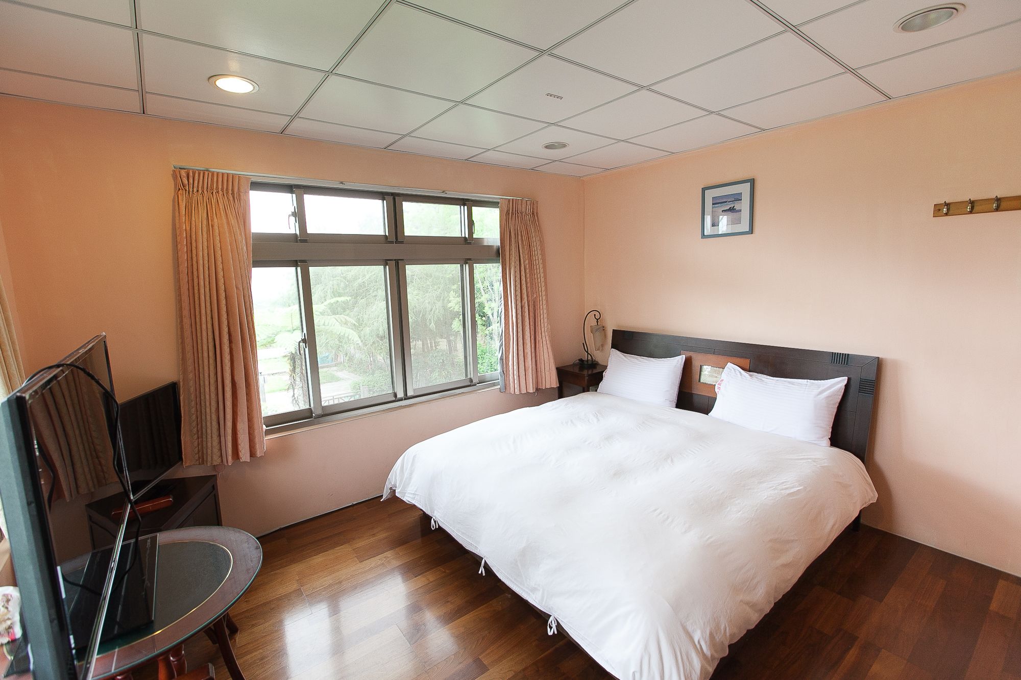 Habitación de hotel con una cama grande, un escritorio y una ventana con cortinas.