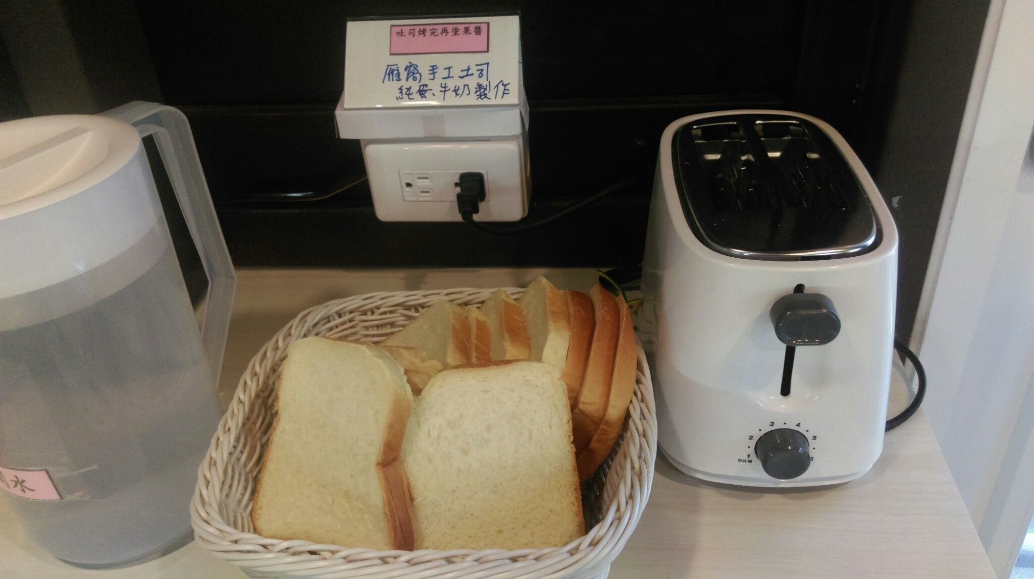 A toaster, a basket of bread, and a water dispenser on a counter.