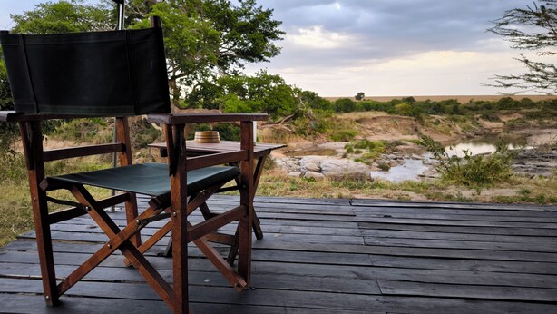 Une terrasse en bois avec une chaise pliante et une petite table sur laquelle se trouvent un bol et une assiette.