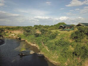 A riverside property with a small house and a covered outdoor area. - Julia's River Camp (Maasai Mara)