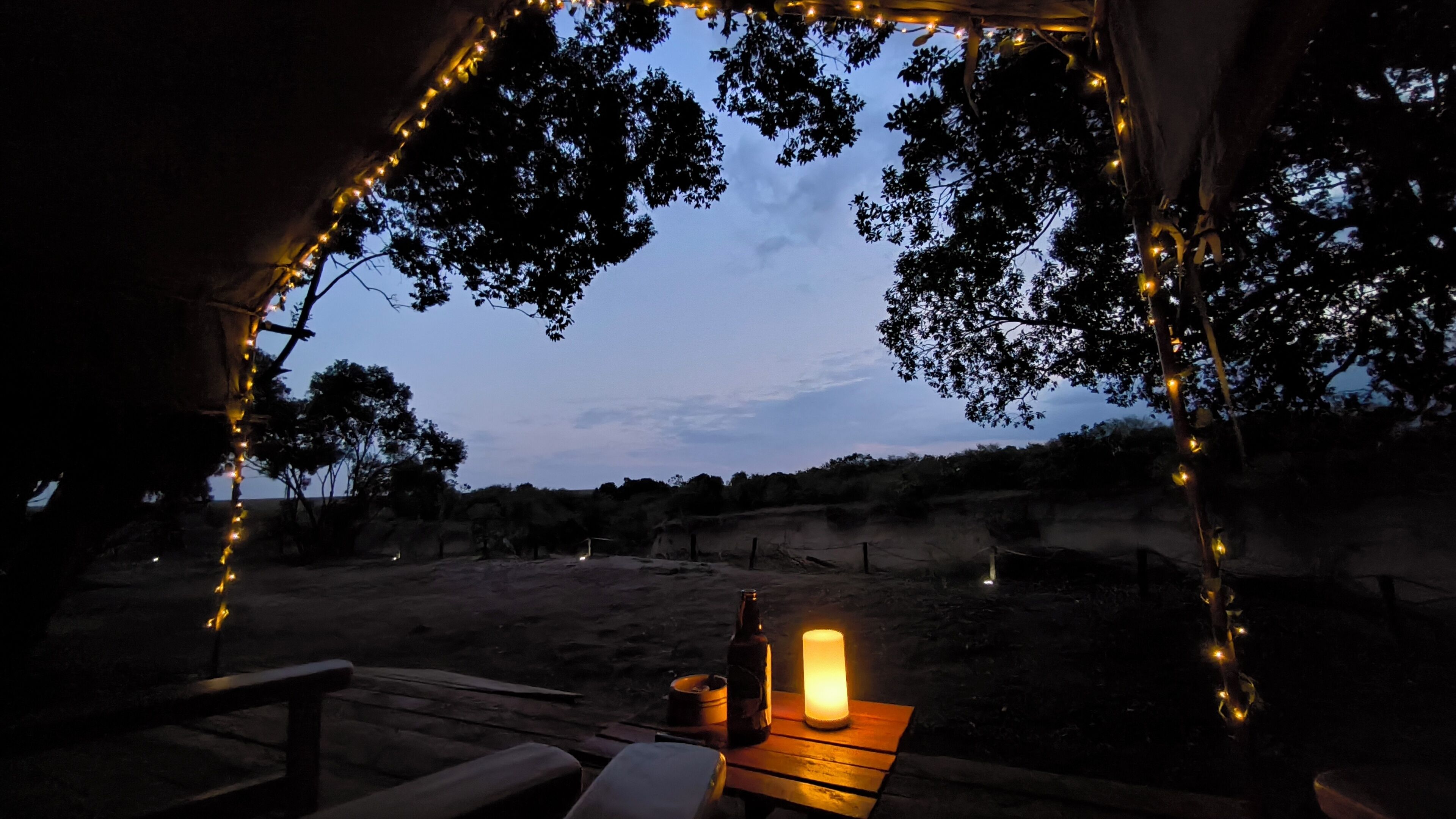 Una carpa con una mesa, una vela y luces colgantes.