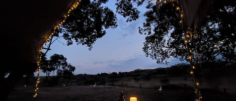 Una carpa con una mesa, una vela y luces colgantes.