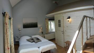 Quarto com uma cama, duas mesinhas de cabeceira, um criado-mudo, uma janela com cortinas, uma luminária na parede e uma porta que dá para outro cômodo.