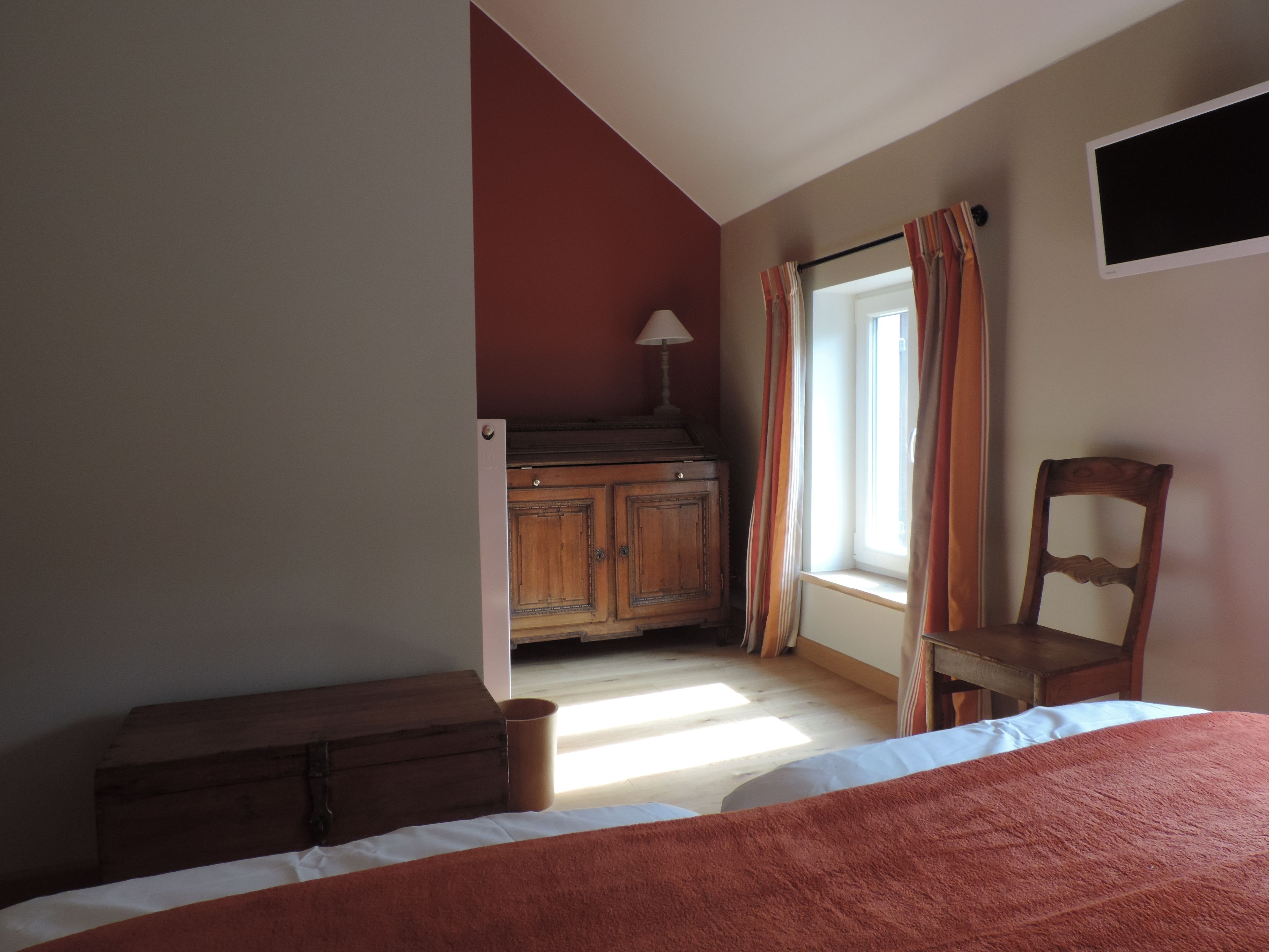 Un dormitorio con cama, cómoda de madera, silla y ventana con cortinas.