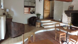 A cozy living room with a fireplace, wooden furniture, and a staircase leading to another room. - B&B Le Valangré (Chaumont-Gistoux)