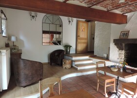 Una sala de estar acogedora con chimenea, muebles de madera y una escalera que conduce a otra habitación.