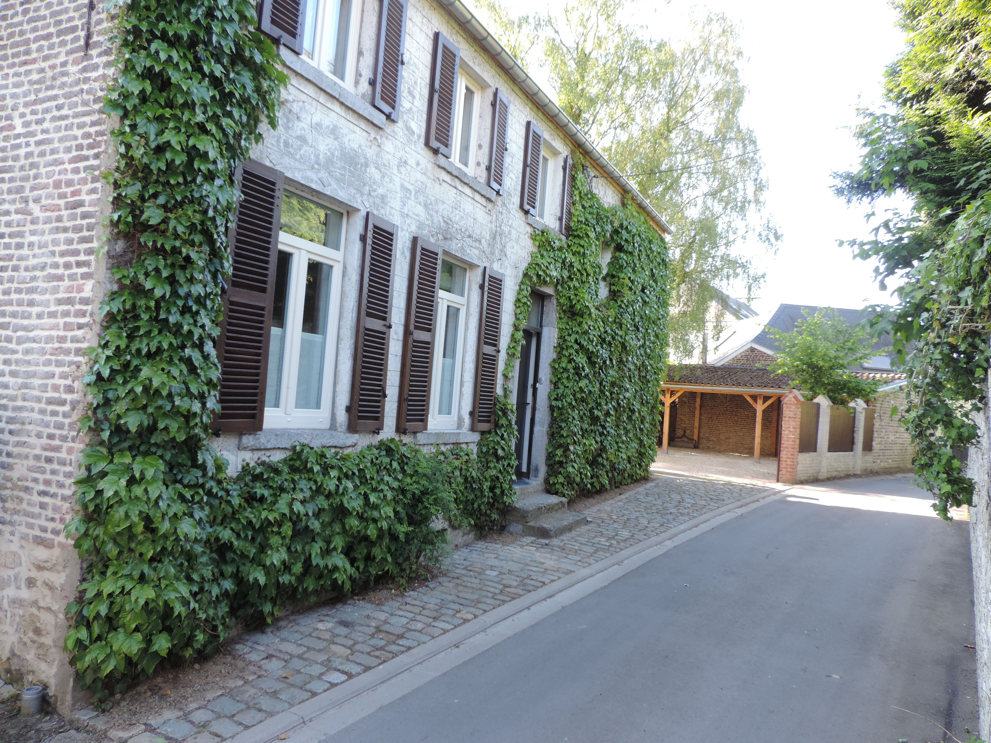 A two-story building with ivy-covered walls and wooden shutters.