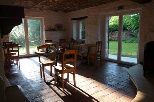 Un comedor rústico con paredes de piedra, muebles de madera y grandes puertas correderas de vidrio que dan a un jardín.