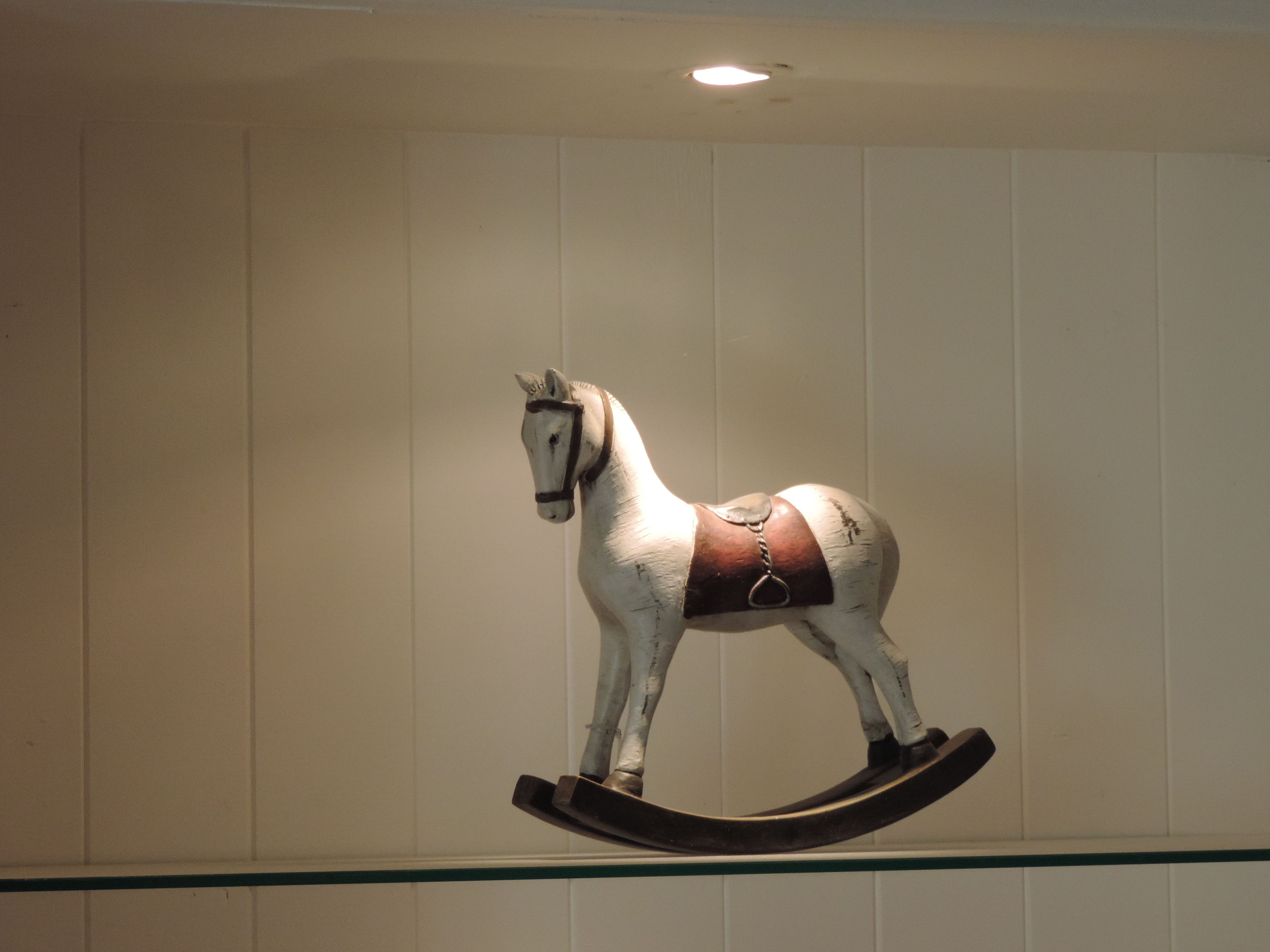 A white rocking horse mounted on a wall.