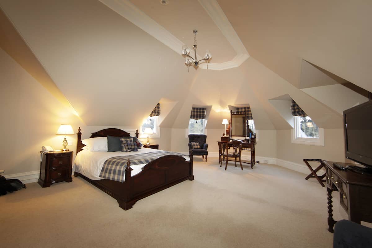 A bedroom with a large bed, a desk, a chair, and a television.