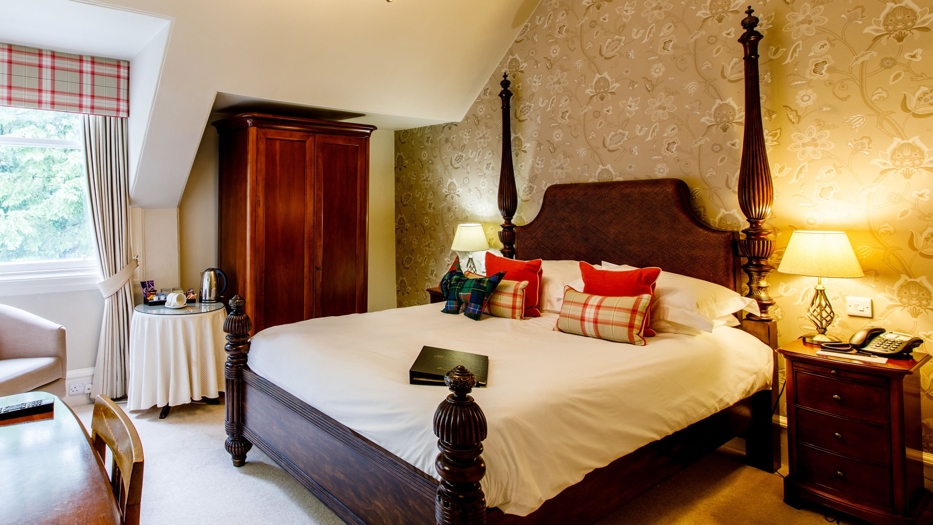 A neatly made bed with a wooden headboard, a bedside table with a lamp, and a chair.