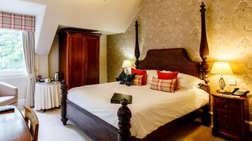 A neatly made bed with a wooden headboard, a bedside table with a lamp, and a chair.