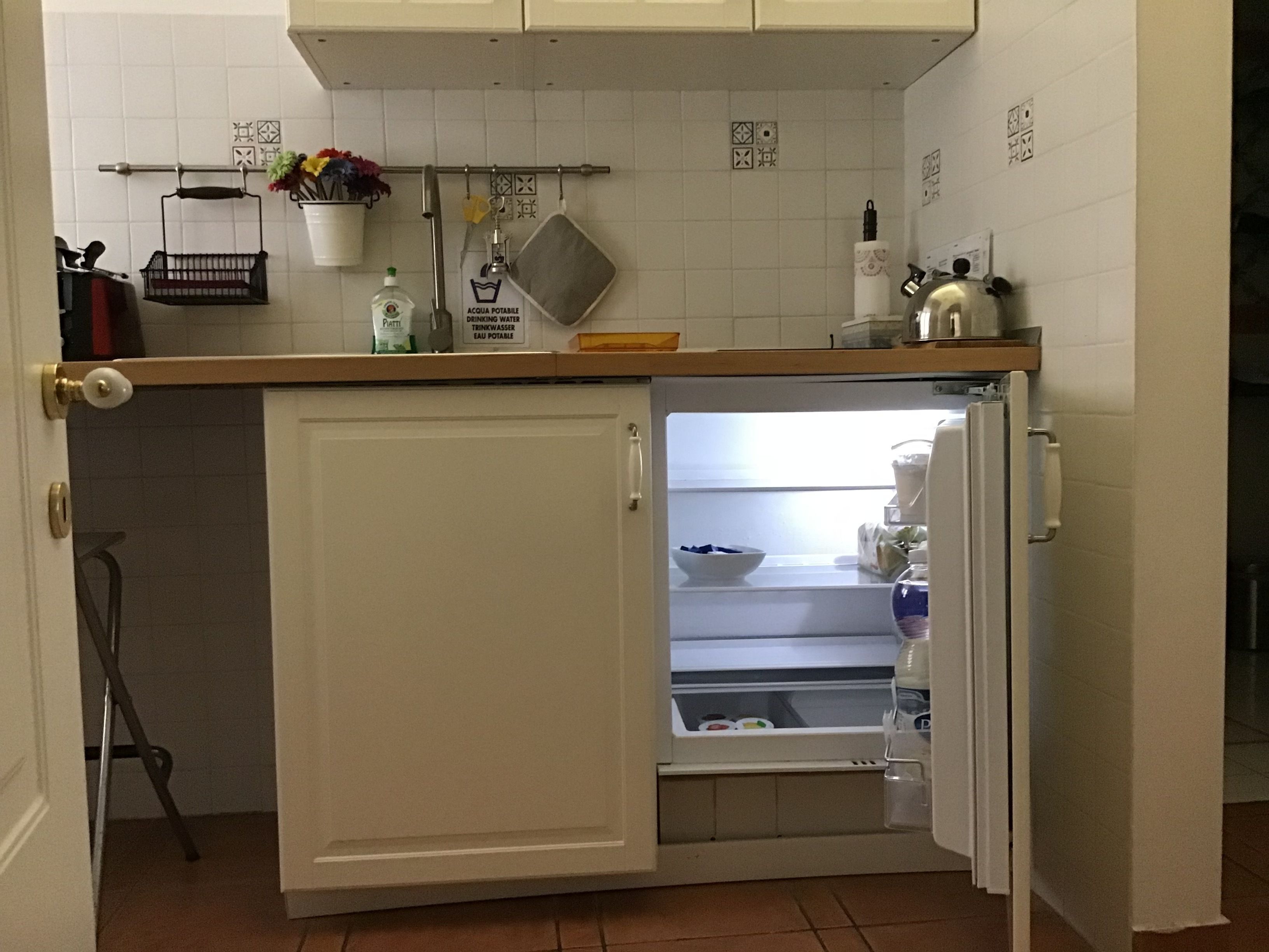 A compact kitchen with a built-in refrigerator and a small pantry.