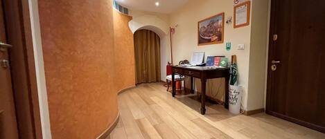 Un couloir avec un plancher en bois, un bureau avec un ordinateur et une porte.