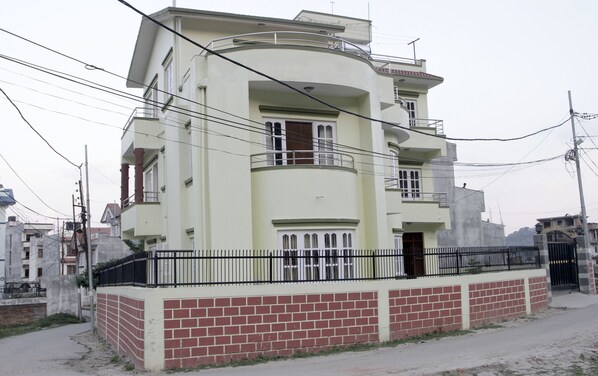 A multi-story building with a curved facade, balconies, and a brick base.