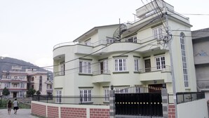 A multi-story residential building with a black gate, balconies, and a brick wall. - Kathmandu Homestay (Kathmandu)
