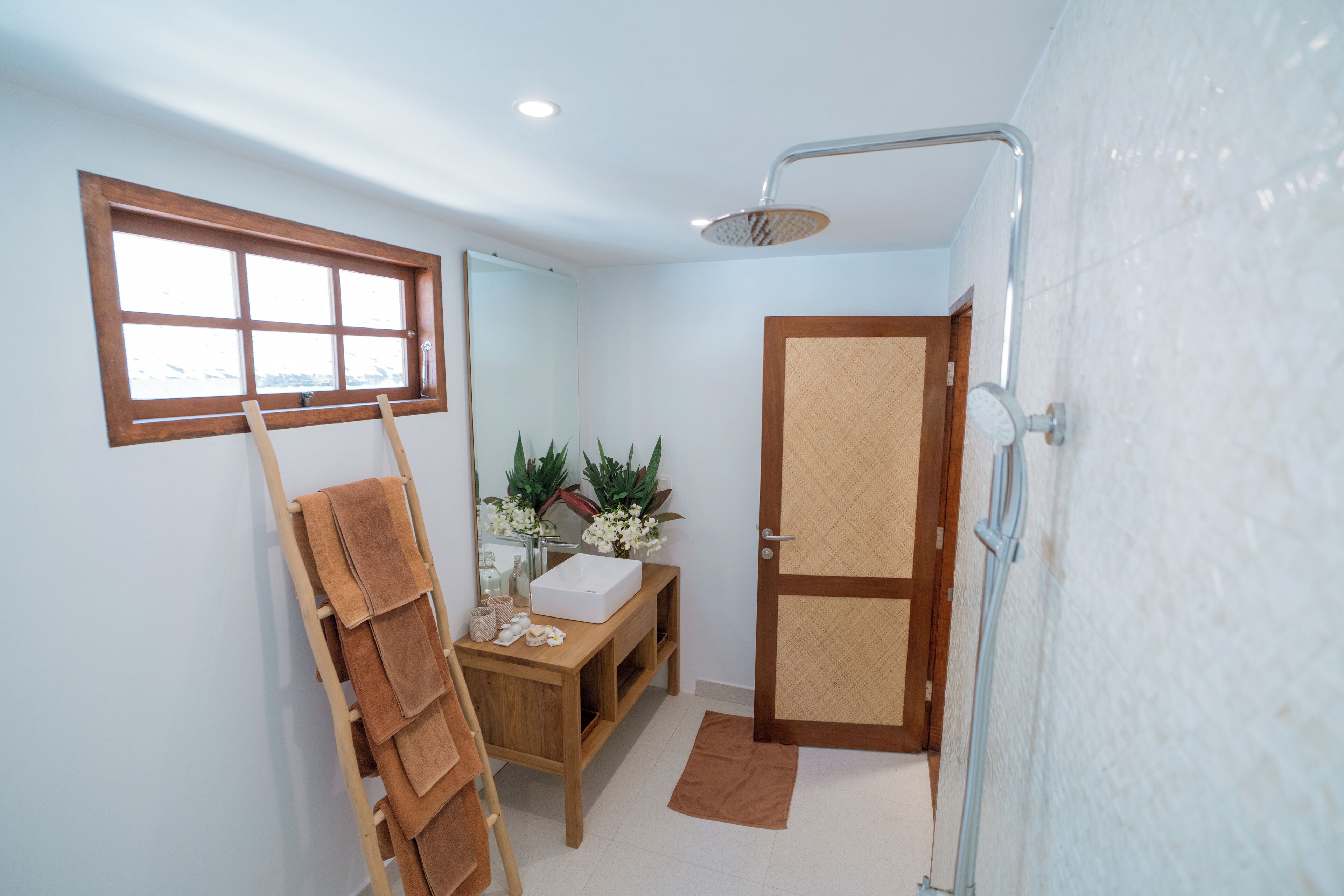 Une salle de bain avec un meuble-lavabo en bois, une douche, un porte-serviettes et une fenêtre.