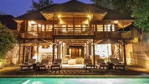 Een houten huis met twee verdiepingen, een balkon, een terras en een zwembad.