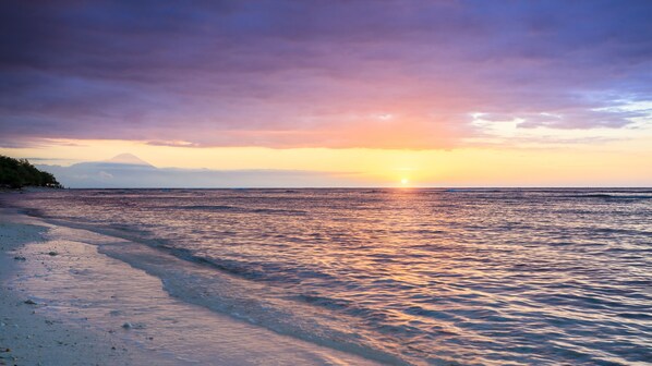 En strand med solnedgang over havet.