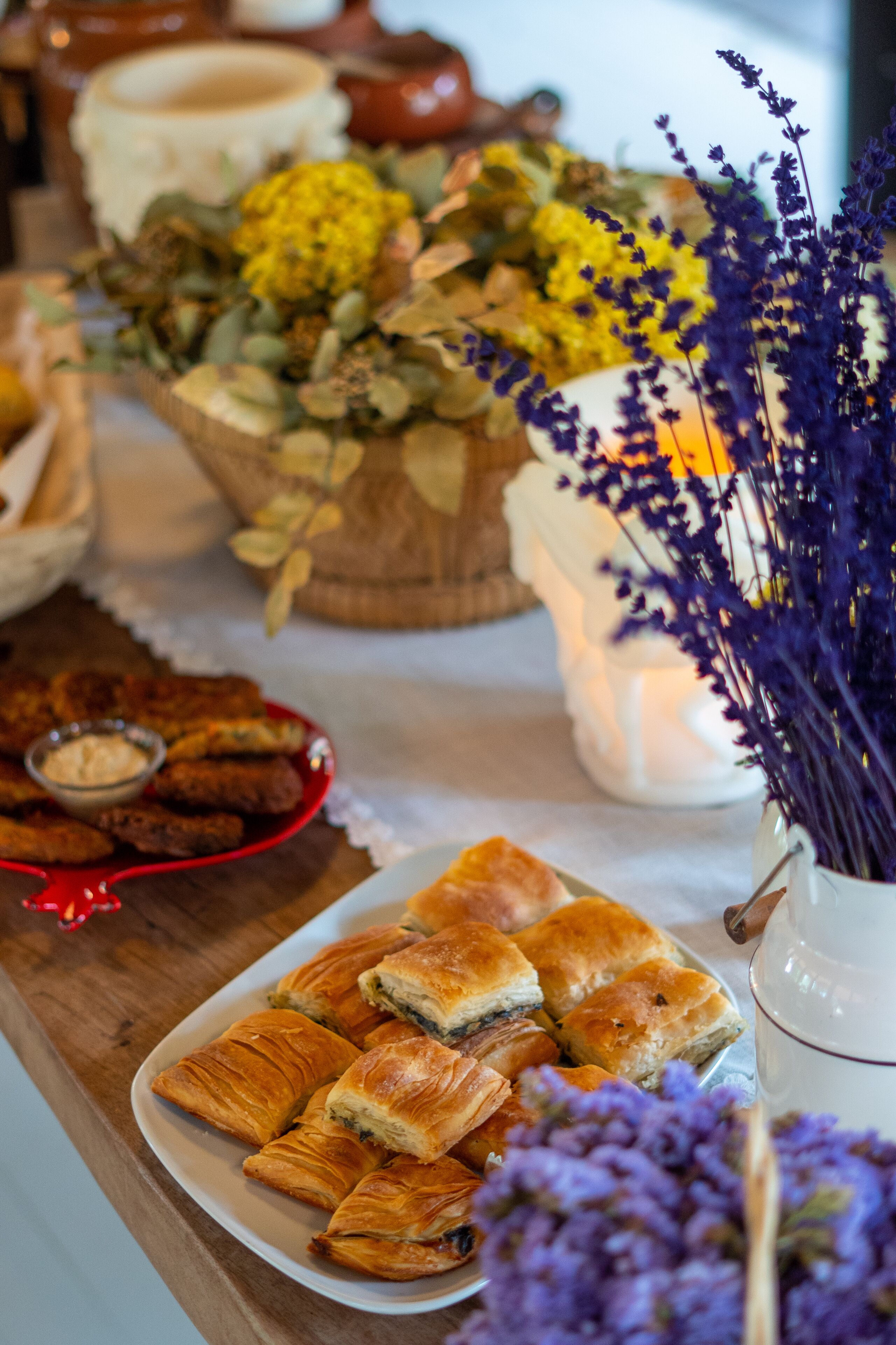 A table with pastries, a bowl of flowers, and a candle.