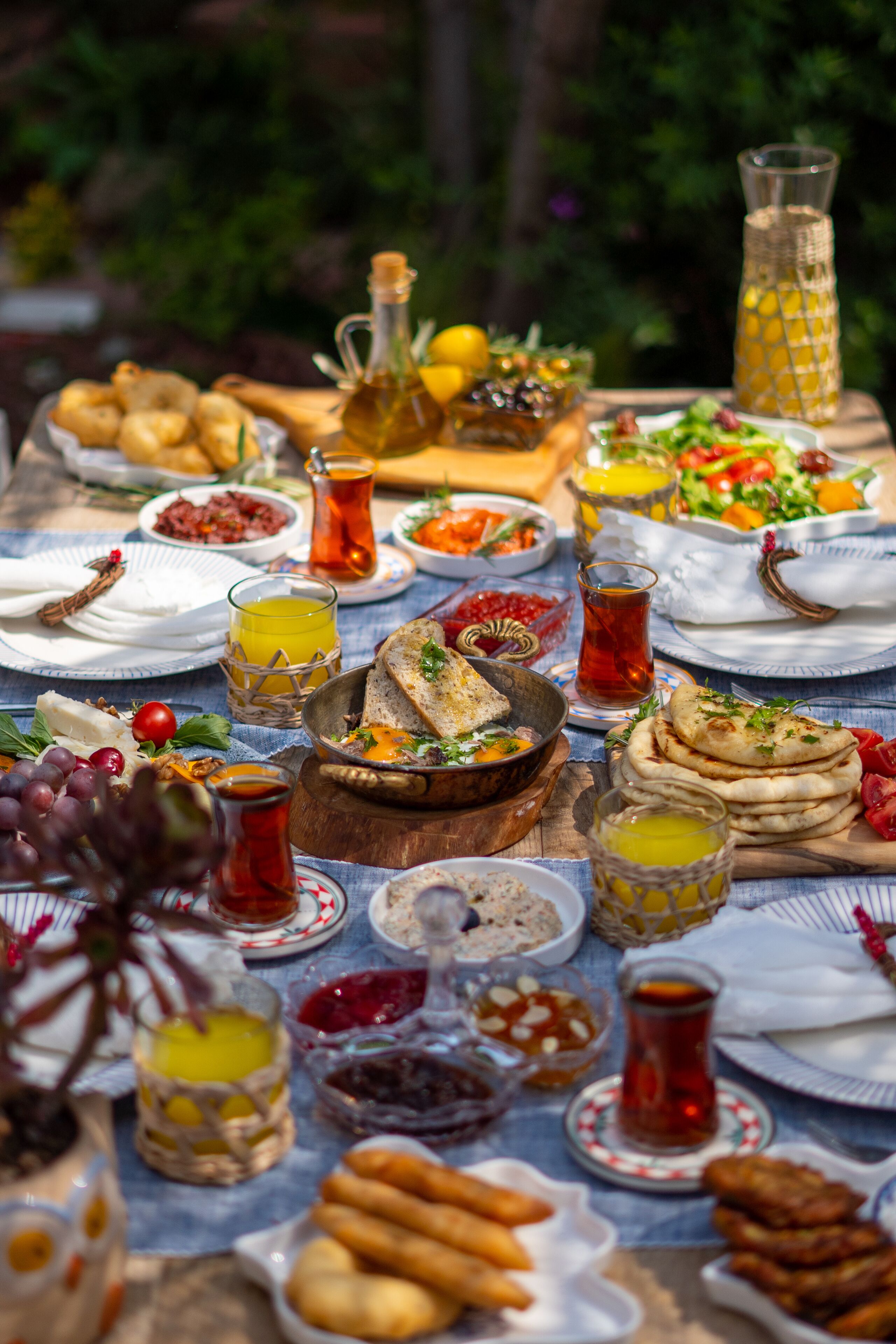 Una mesa dispuesta con diferentes platos, incluyendo pan, ensaladas y bebidas, lo que sugiere un ambiente para comer.