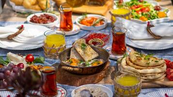 Una mesa dispuesta con diferentes platos, incluyendo pan, ensaladas y bebidas, lo que sugiere un ambiente para comer.