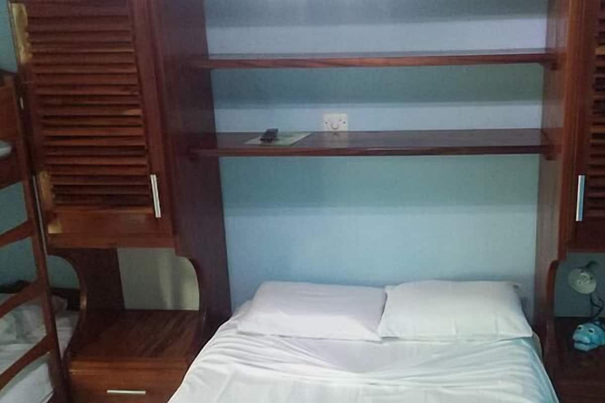 Um quarto com uma cama beliche, uma escrivaninha com cadeira e uma pequena mesa com ventoinha.