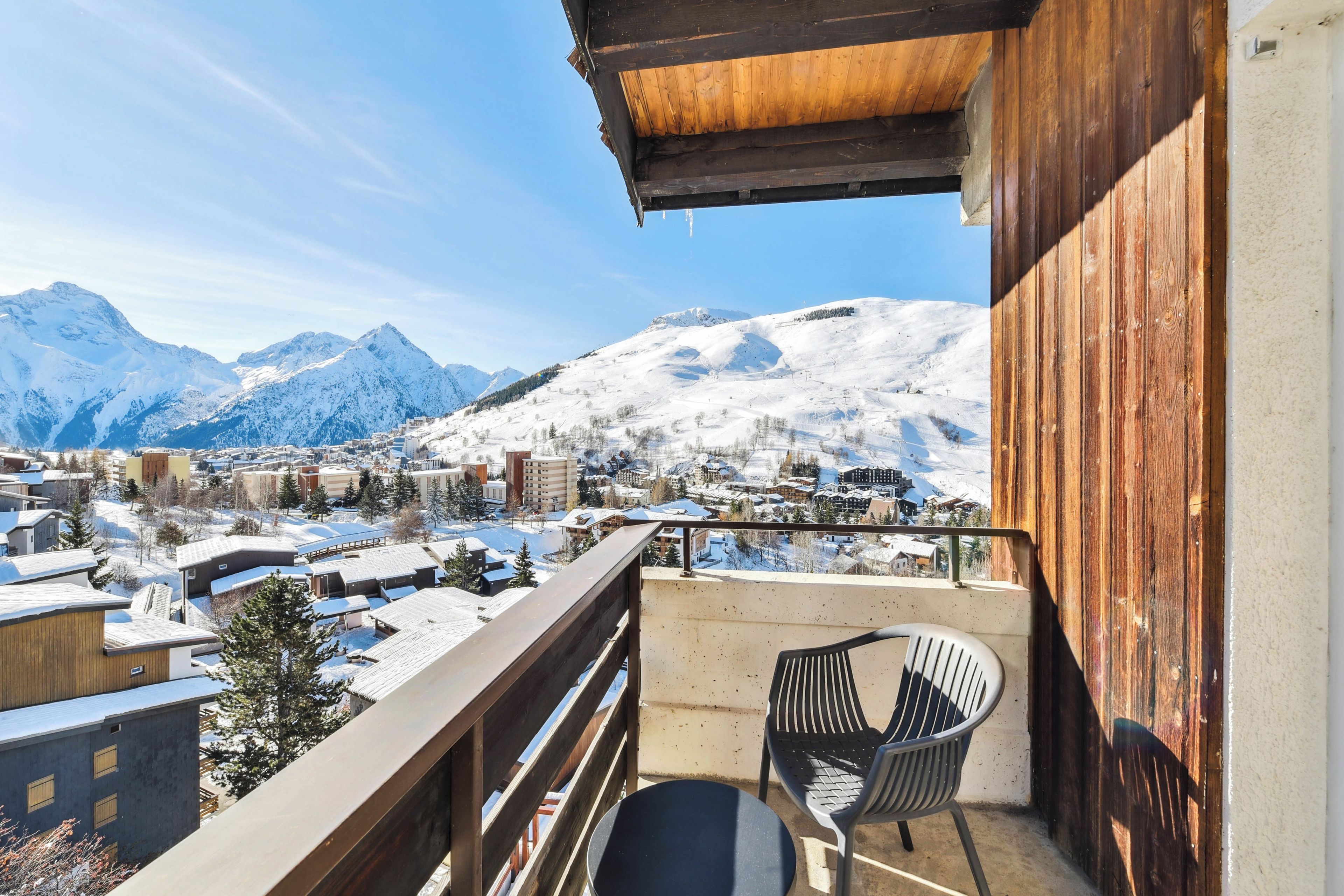 Ein Balkon mit Blick auf verschneite Berge und eine Stadt darunter.