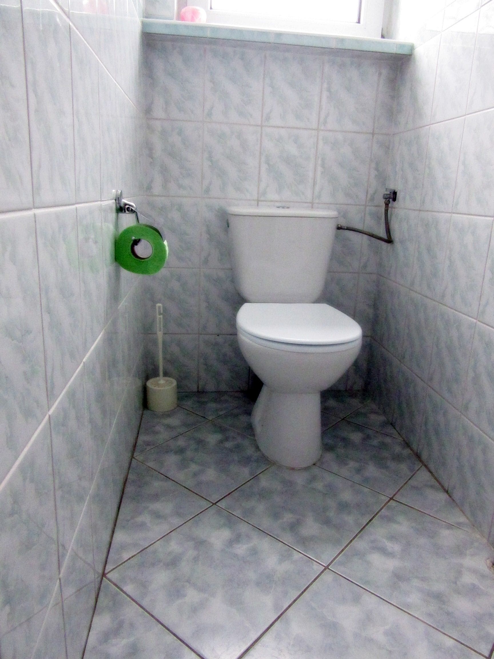 A small bathroom with a toilet, a toilet paper holder, and a bidet.