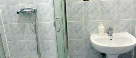 A bathroom with a glass-enclosed shower, a pedestal sink, and a toilet.