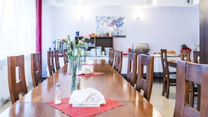 Un comedor con una larga mesa de madera, individuales rojos y un jarrón con flores.