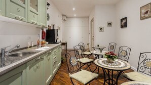 Una cocina con pileta, alacenas y un comedor con sillas y mesa.