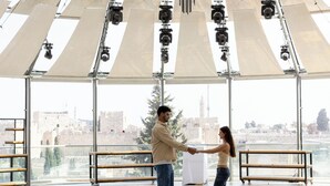 A spacious indoor area with a high ceiling and large windows, featuring a couple holding hands. - Hotel Beit Shmuel (Jerusalem)