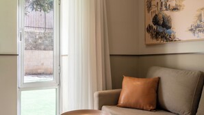 A room with a sofa, a table with a bowl, a painting on the wall, and a window with curtains. - Hotel Beit Shmuel (Jerusalem)
