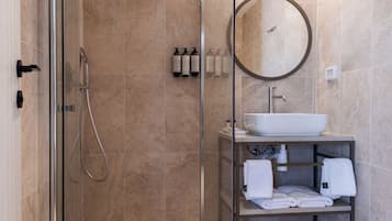Une salle de bain moderne avec une douche à parois de verre, un miroir rond et un lavabo doté d’un porte-serviettes.