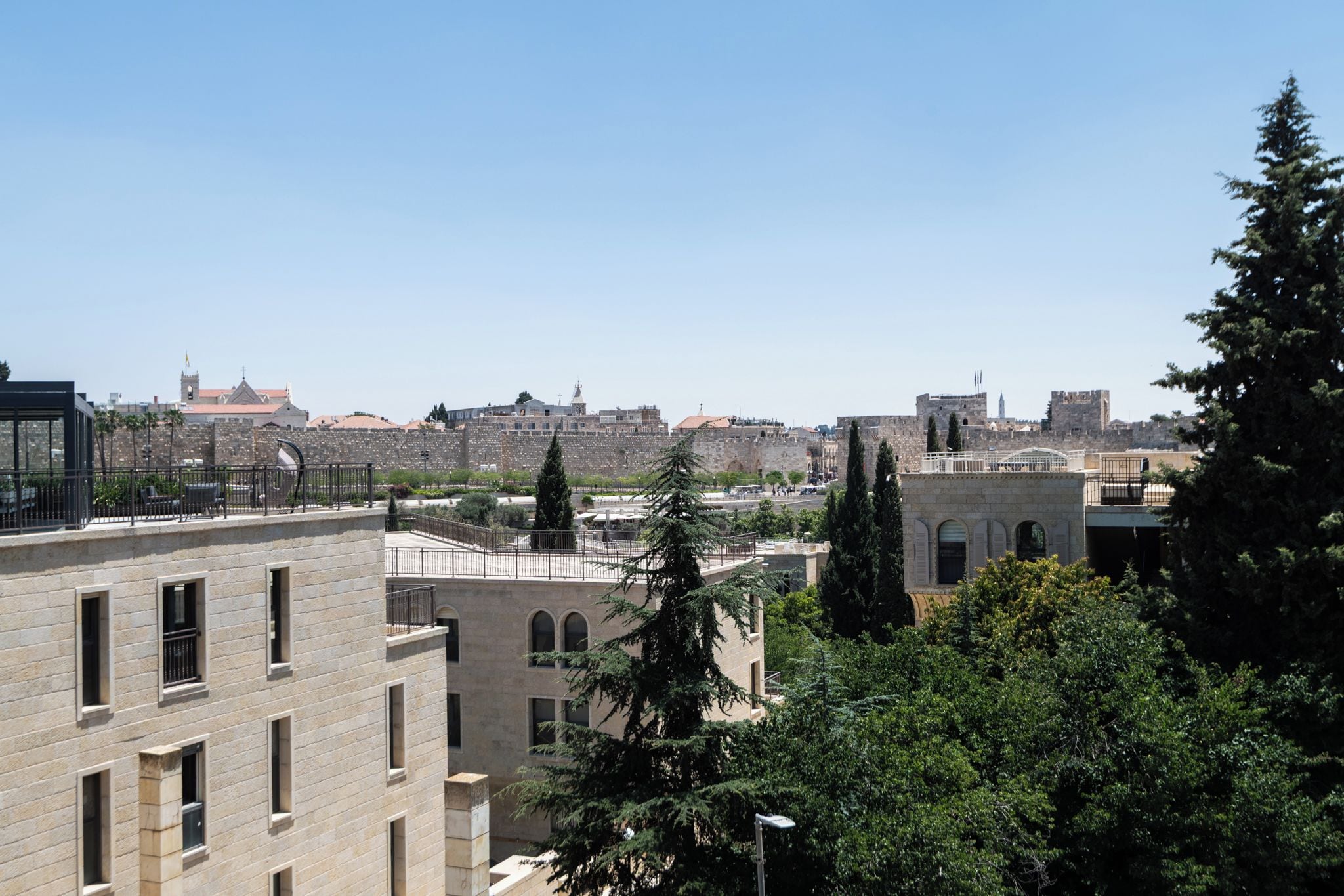 A view of a cityscape with historical buildings, a clear sky, and some greenery.