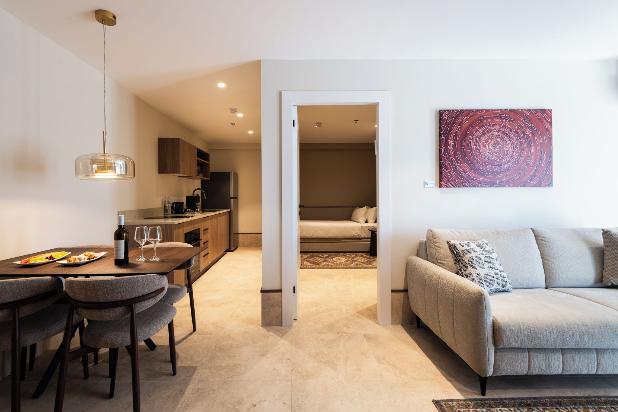 Een modern appartement met een eetgedeelte, kitchenette en een woonkamer met een bank en vloerkleed.