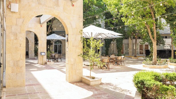An outdoor courtyard with stone arches, outdoor seating, and string lights. - Hotel Beit Shmuel (Jerusalem)