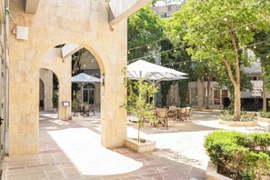 An outdoor courtyard with stone arches, outdoor seating, and string lights. - Hotel Beit Shmuel (Jerusalem)
