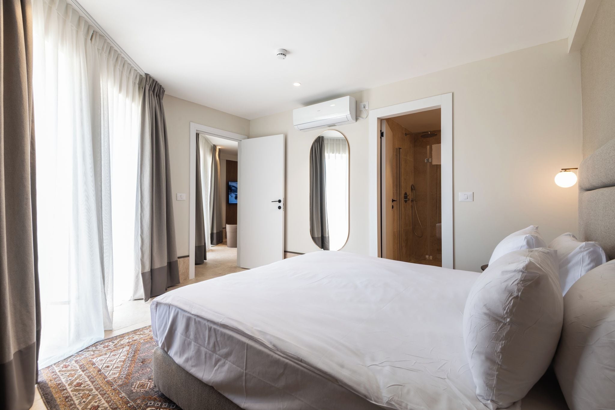 Ein Hotelzimmer mit einem großen Bett, einer Dusche, einem Spiegel und einem Fernseher.