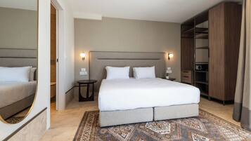 A hotel room with a large bed, bedside tables, a wardrobe, and a patterned rug.
