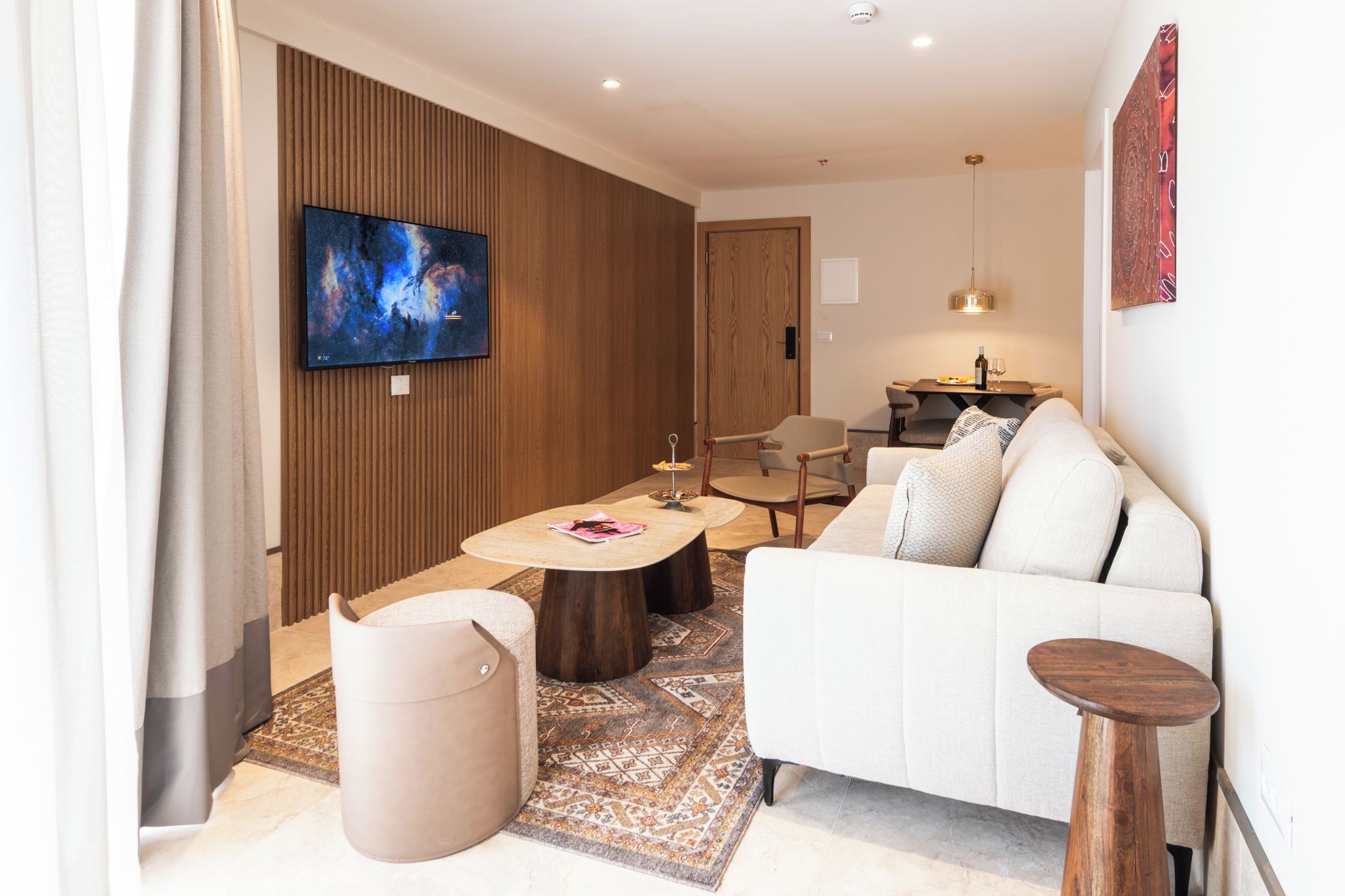 A modern living room with a flat-screen TV, a sofa, a coffee table, and a dining area.