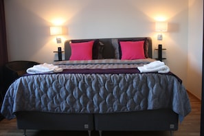 A neatly made bed with a checkered bedspread, two pillows, and two bedside lamps. - Hotell Lyktan (Arjeplog)