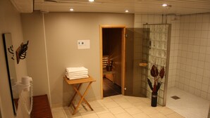 A bathroom with a bench, a towel rack, and a glass shower enclosure. - Hotell Lyktan (Arjeplog)