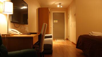 Ett hotellrum med ett skrivbord, en stol, en säng och en spegel.