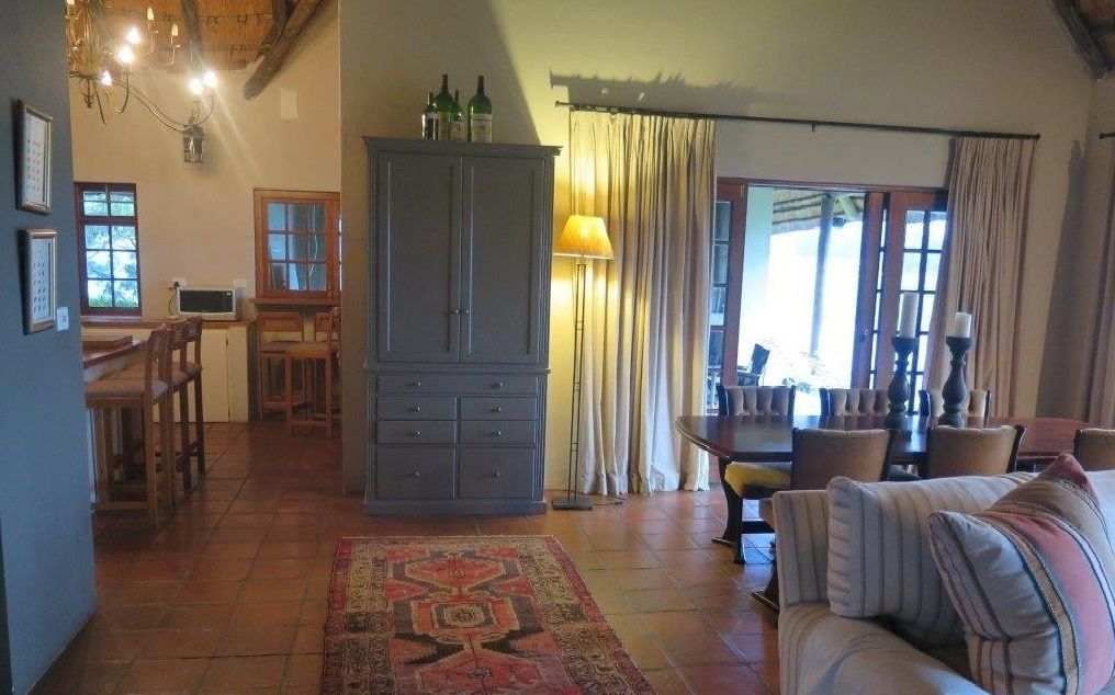 A spacious living area with a dining table, a sofa, a cabinet, and a patterned rug.
