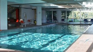 A swimming pool with clear water, surrounded by a covered area with chairs and tables. - TH 1400 (Mezzana)