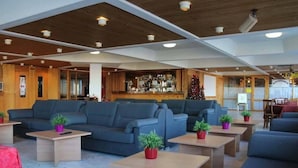 A spacious lobby with multiple seating areas, a bar, and a Christmas tree. - TH 1400 (Mezzana)